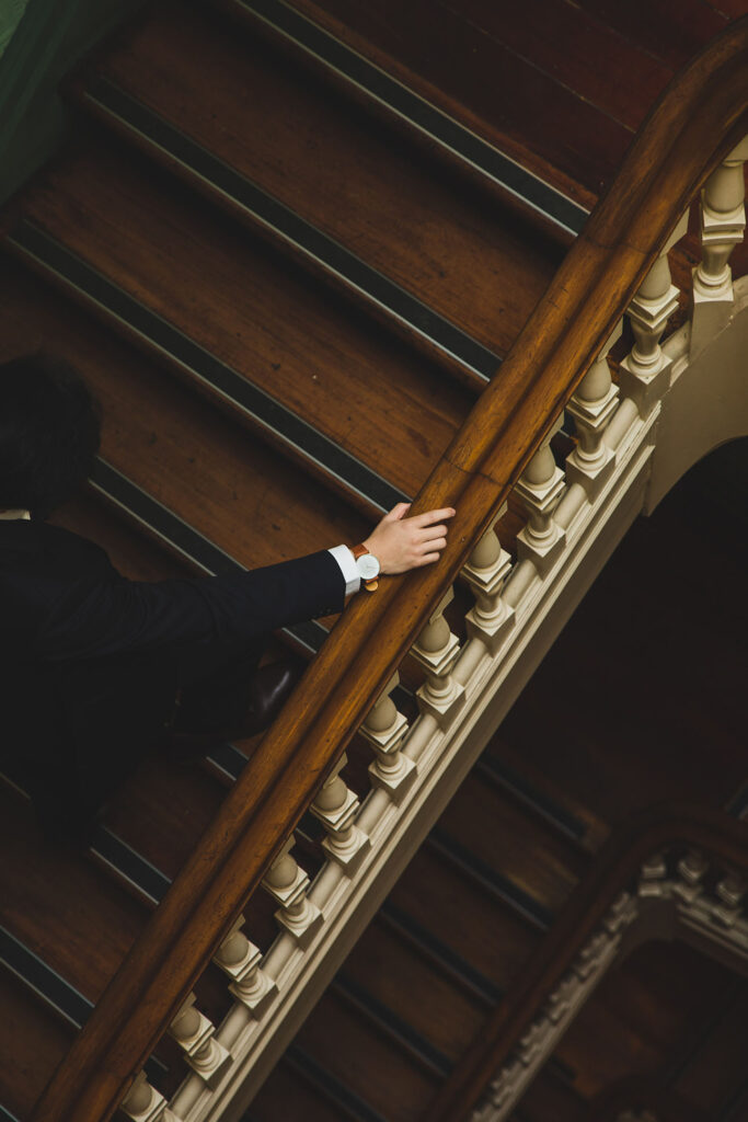 Overhead shot of a staircase with a man walking upstairs. The photo focuses on the luxury watch.