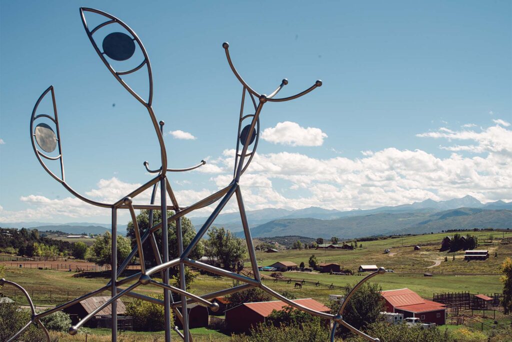 a metal sculpture of a fish with a view of a valley and mountains