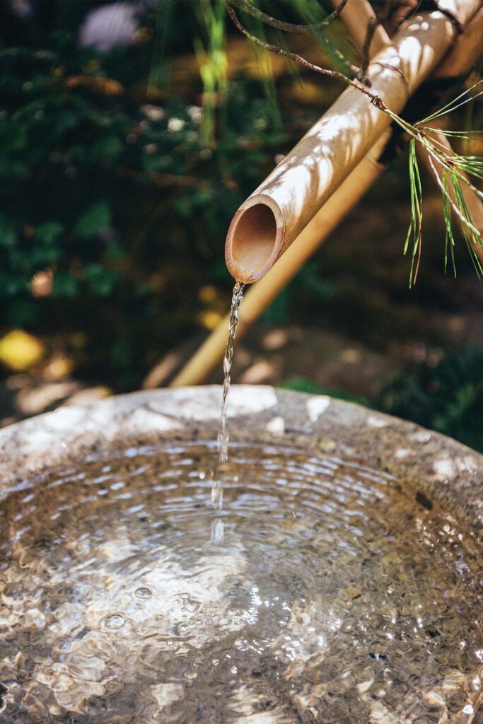 a water pouring out of a bamboo pipe into a water fountain