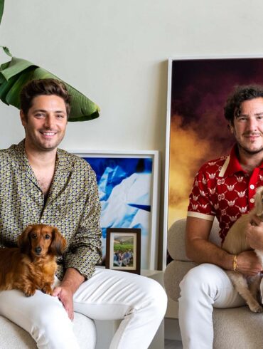 two men sitting in chairs with dogs