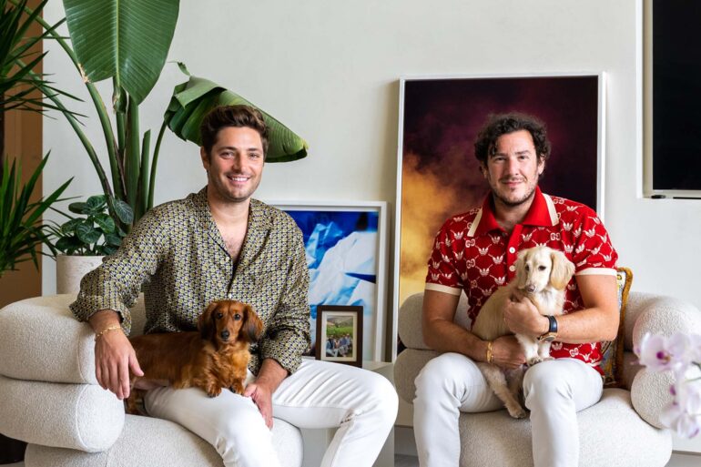 two men sitting in chairs with dogs