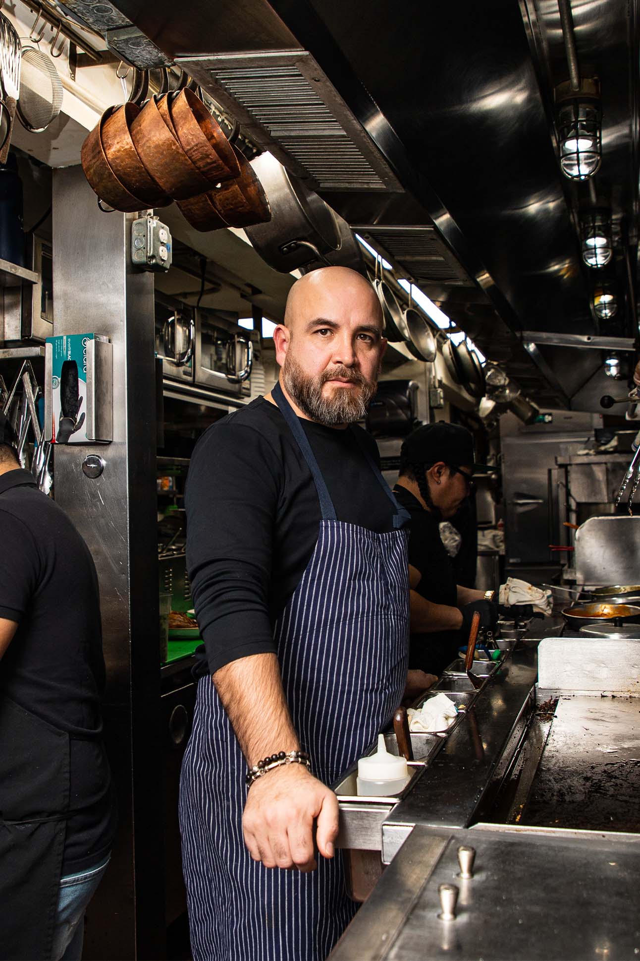 Aguilar standing inside of a kitchen wearing a striped apron